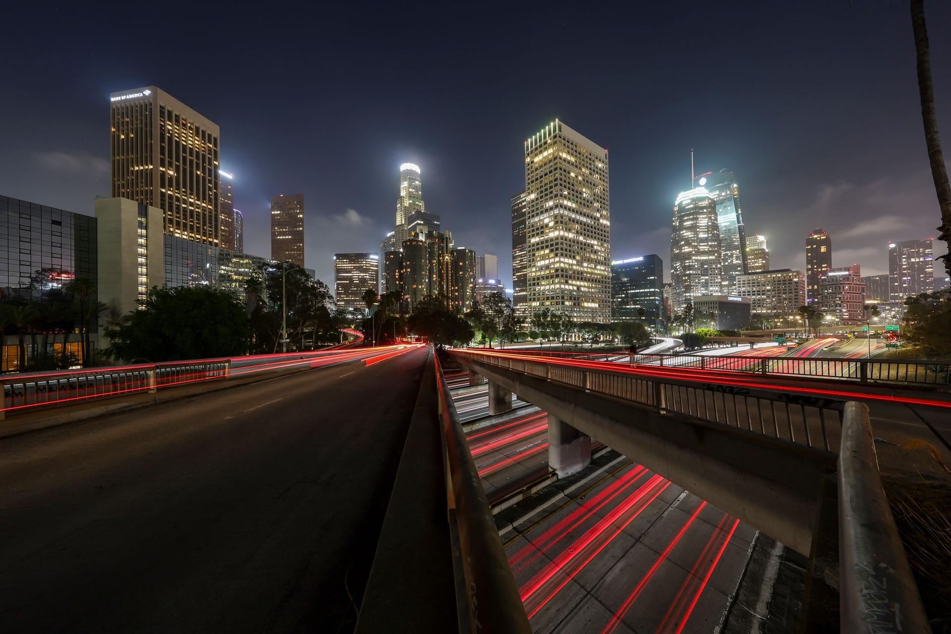 Downtown Los Angeles skyline at night with light trails from freeway traffic