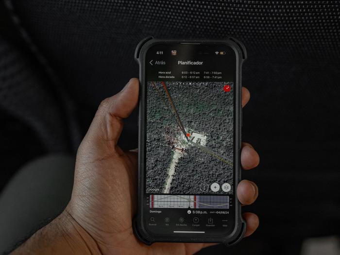 A hand holding a smartphone that shows a map, inside a vehicle
